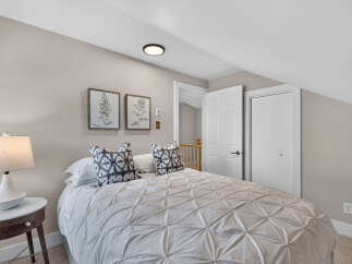 Discover comfort and style in this inviting bedroom, featuring a plush queen-size bed adorned with decorative pillows and a textured duvet.