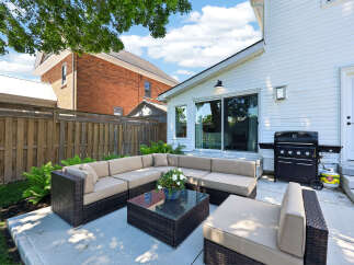 Enjoy outdoor living with this spacious patio featuring a large sectional sofa and a coffee table, perfect for entertaining guests.