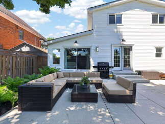 Enjoy outdoor living at its finest with this spacious patio featuring a large sectional sofa and a modern coffee table, perfect for entertaining guests.