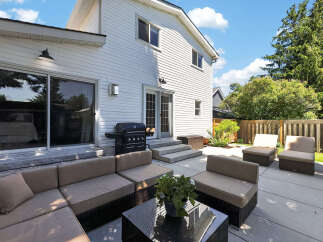 Enjoy outdoor living with this spacious patio featuring comfortable sectional seating and accent chairs, perfect for entertaining.