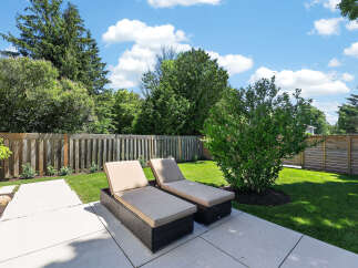 Enjoy the outdoors in this beautifully landscaped backyard, complete with a spacious patio and comfortable lounge chairs perfect for soaking up the sun.