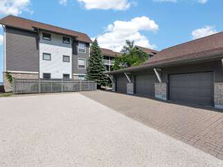Discover modern living with this stunning property featuring a multi-story building with a mix of dark grey and white siding, complemented by a brown shingled roof.