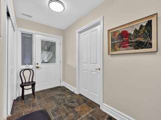 Step into this inviting entryway featuring a charming dark wood chair and a striking abstract landscape painting.