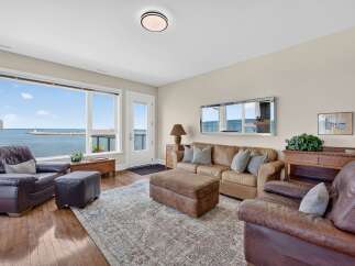Experience breathtaking ocean views from this stunning living room, featuring a comfortable leather sofa and armchair perfect for relaxing.