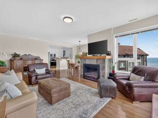 Experience breathtaking waterfront living in this stunning living room, featuring a cozy fireplace and a large window with panoramic ocean views.
