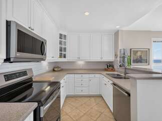 This spacious kitchen features sleek white cabinetry and a modern stainless steel microwave and range.