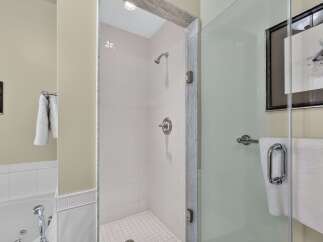 Experience luxury in this modern bathroom featuring a spacious walk-in shower with pristine white tile and a sleek glass enclosure.