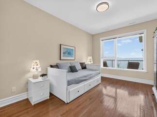 Experience breathtaking waterfront views from this charming bedroom, featuring a comfortable daybed and ample storage.