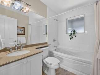 This bright and clean bathroom features a spacious vanity with a granite countertop and a large mirror, perfect for your morning routine.
