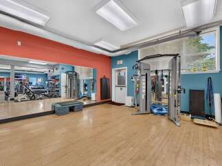 This spacious gym features a variety of modern exercise equipment, including a cable crossover machine and free weights, perfect for a comprehensive workout.