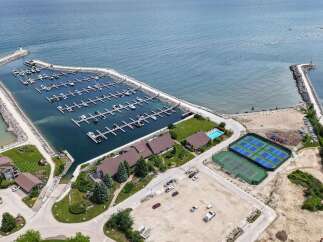Experience luxury waterfront living with this stunning aerial view of a marina, complete with private docks and a lighthouse.