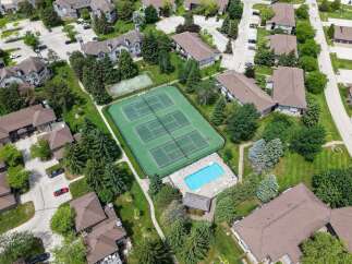 Discover resort-style living with this aerial view showcasing a vibrant community featuring multiple tennis courts and a sparkling blue swimming pool.