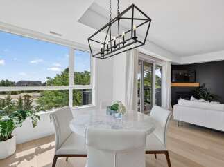 Experience modern living in this bright and airy dining area, featuring a stunning marble-top table surrounded by elegant white chairs.