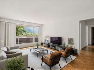 Experience breathtaking mountain views from this stunning living room, featuring a comfortable grey sectional sofa and two stylish leather armchairs.