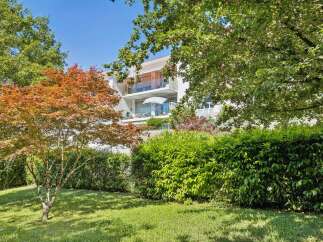 Experience modern living in this stunning apartment building, surrounded by lush greenery and mature trees.