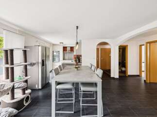 Discover this spacious open-concept living area, perfect for entertaining, featuring a modern kitchen with stainless steel appliances and a large dining table.