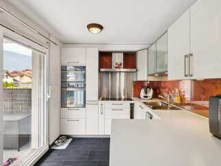 Experience modern living in this sleek kitchen featuring integrated stainless steel appliances, including double ovens and a sophisticated range hood.