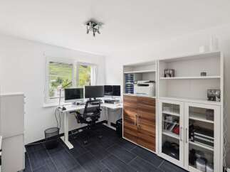 This modern home office features a spacious white desk with multiple monitors, perfect for productivity.