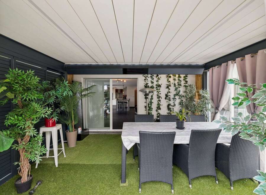 Enjoy outdoor living in this covered patio space, complete with artificial turf flooring and a dining set perfect for al fresco meals.