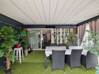 Enjoy outdoor living in this covered patio space, complete with artificial turf flooring and a dining set perfect for al fresco meals.