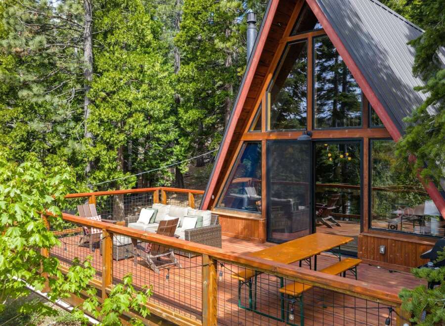 Experience the ultimate mountain retreat in this stunning A-frame cabin, nestled amongst lush green trees.