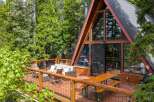 Experience the ultimate mountain retreat in this stunning A-frame cabin, nestled amongst lush green trees.