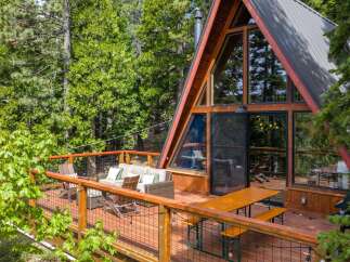 Experience the ultimate mountain retreat in this stunning A-frame cabin, nestled amongst lush green trees.