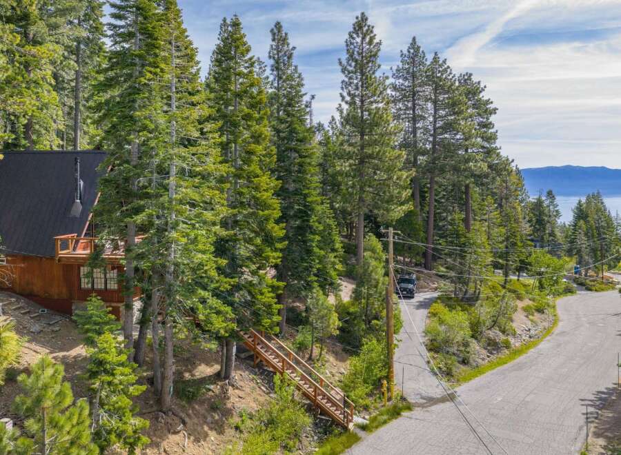 Nestled amidst towering pine trees, this charming wooden cabin offers a serene mountain retreat with stunning lake views in the distance.