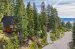 Nestled amidst towering pine trees, this charming wooden cabin offers a serene mountain retreat with stunning lake views in the distance.