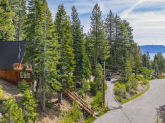 Nestled amidst towering pine trees, this charming wooden cabin offers a serene mountain retreat with stunning lake views in the distance.
