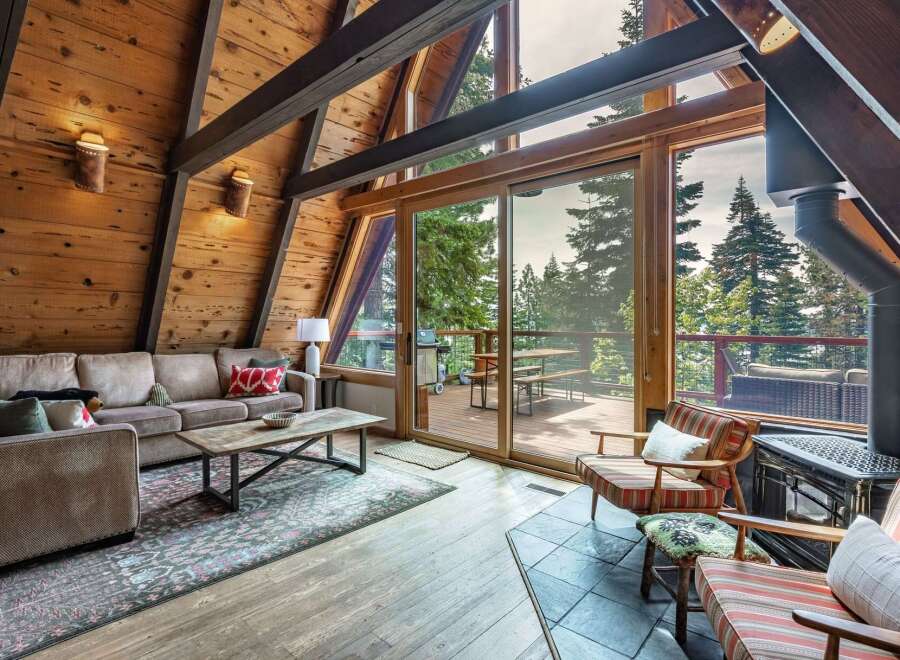 Experience rustic charm in this A-frame cabin living room, featuring a plush sectional sofa and a rustic wood coffee table.