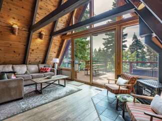 Experience rustic charm in this A-frame cabin living room, featuring a plush sectional sofa and a rustic wood coffee table.