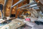 Experience rustic charm in this A-frame cabin living space, featuring a cozy fireplace, a well-equipped kitchen, and a dining area perfect for gathering.