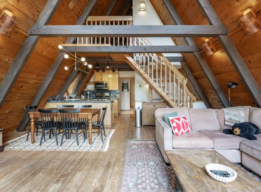 Experience rustic charm in this A-frame cabin featuring a spacious open-concept living area with a dining space and modern kitchen.