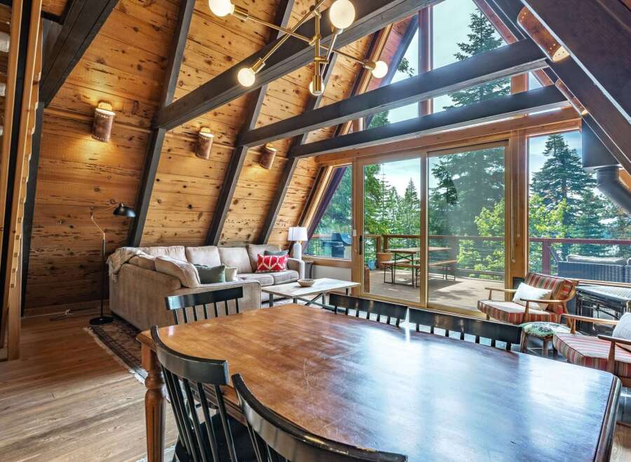Experience rustic charm in this A-frame cabin living room, featuring a spacious dining area with a large wooden table and seating for six.