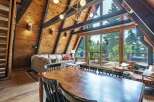 Experience rustic charm in this A-frame cabin living room, featuring a spacious dining area with a large wooden table and seating for six.