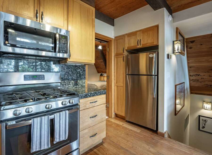 Experience rustic charm in this cozy kitchen featuring stainless steel appliances, including a microwave and gas range, complemented by elegant granite countertops.