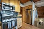 Experience rustic charm in this cozy kitchen featuring stainless steel appliances, including a microwave and gas range, complemented by elegant granite countertops.