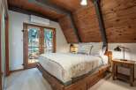 Experience rustic charm in this cozy bedroom featuring a wooden A-frame ceiling and exposed beams.