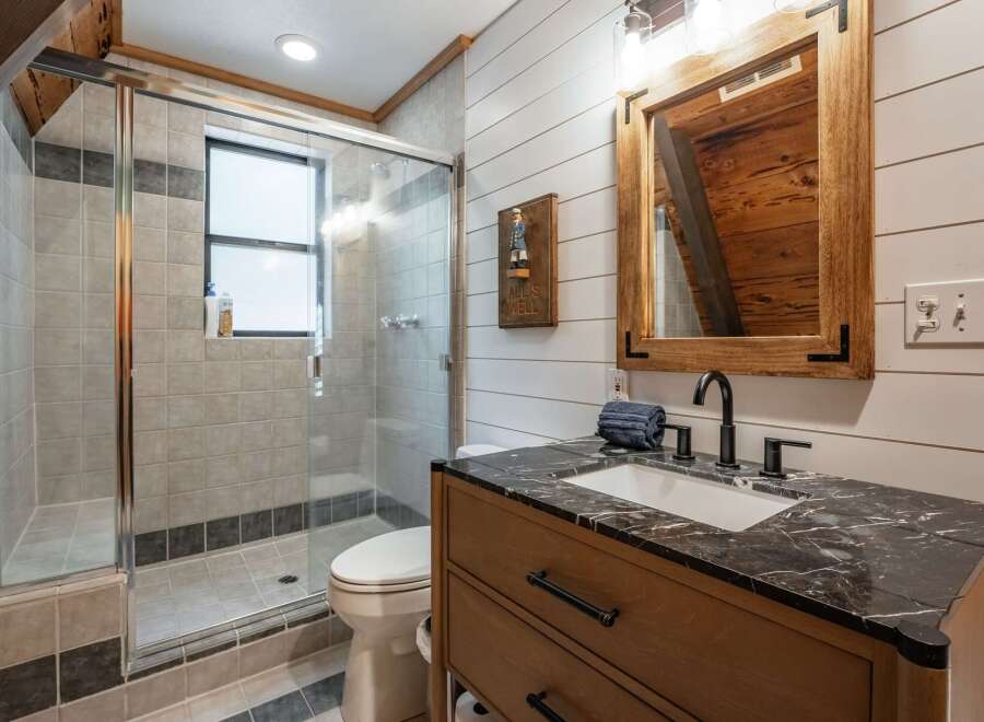 This charming bathroom features a spacious glass-enclosed shower with tiled walls and a convenient window for natural light.