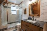 This charming bathroom features a spacious glass-enclosed shower with tiled walls and a convenient window for natural light.