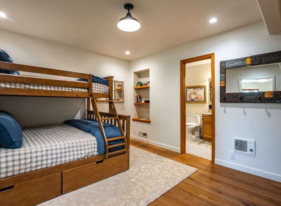 This charming bedroom features a sturdy wooden bunk bed with built-in drawers, perfect for maximizing space and accommodating guests.