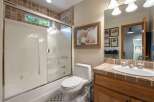 This charming bathroom features a spacious bathtub/shower combo with a sliding glass door and elegant tile accents.