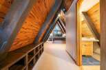 Experience unique A-frame living with this charming bedroom featuring rustic wooden beams and a cozy lofted feel.