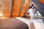 Experience rustic charm in this A-frame bedroom, featuring warm wood-paneled walls and exposed beams that create a cozy, cabin-like atmosphere.