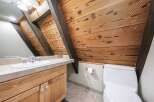Experience rustic charm in this unique bathroom featuring exposed wooden beams and a slatted wood ceiling.
