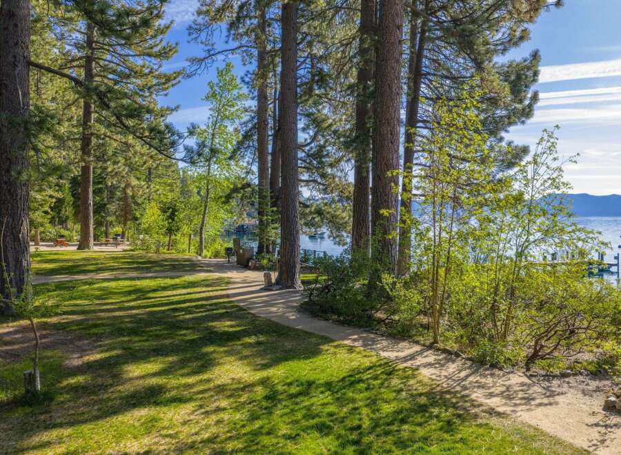 Enjoy serene lakefront living with this stunning property, featuring a lush green lawn perfect for outdoor activities and a scenic path leading to the water.