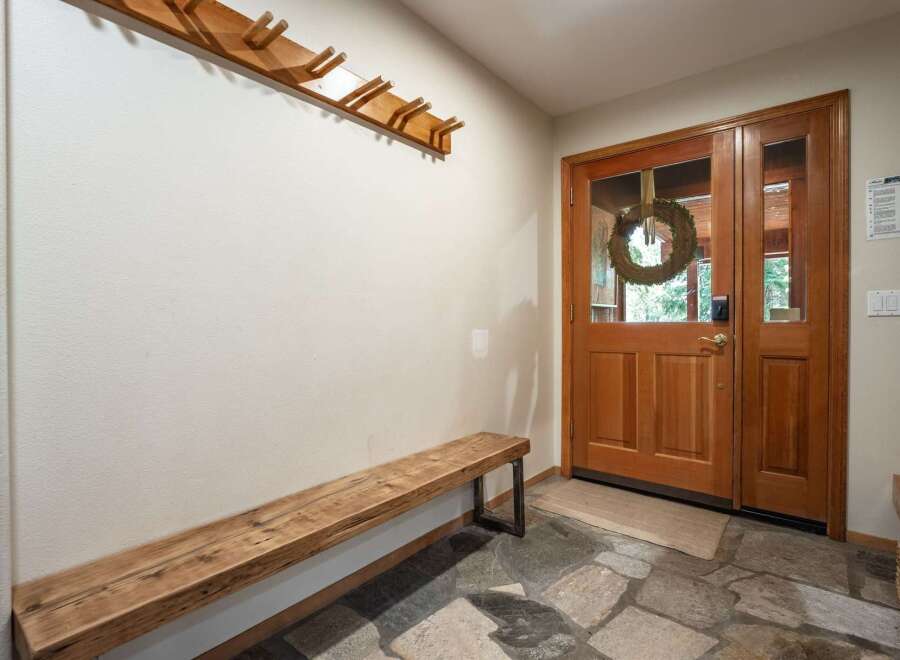 Welcome guests into this charming entryway featuring a rustic wooden bench and a convenient coat rack.
