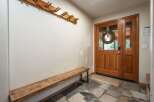 Welcome guests into this charming entryway featuring a rustic wooden bench and a convenient coat rack.