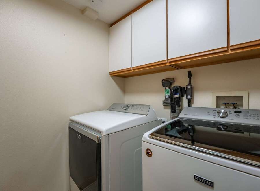 This laundry room features a spacious layout with two modern washing machines, including a Maytag model, ready for your laundry needs.